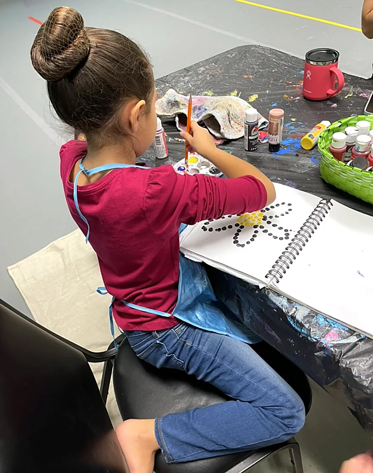 A young artist painting a dot flower at ArtHaus