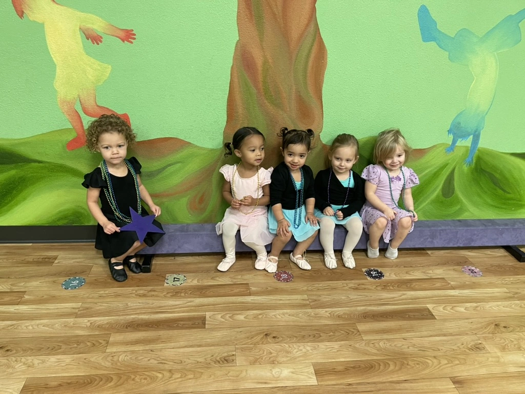 Five Bravo Babies toddlers sitting together on a bench in their dance clothes
