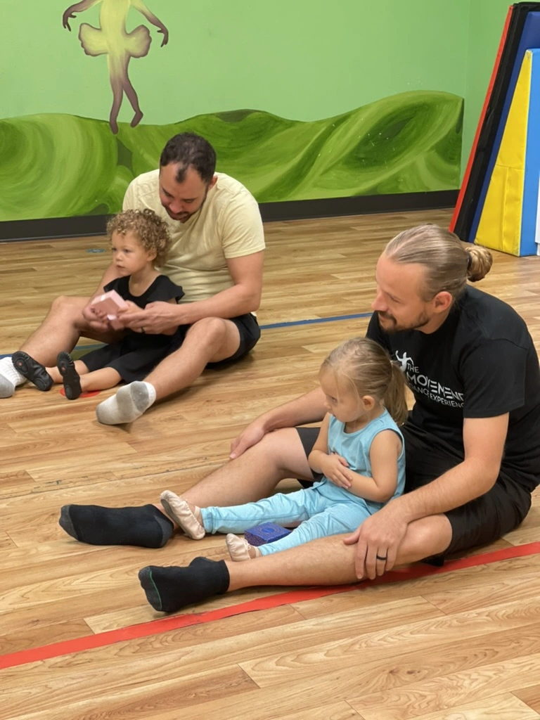 Dads and toddlers sitting together in a Parent and Me dance class