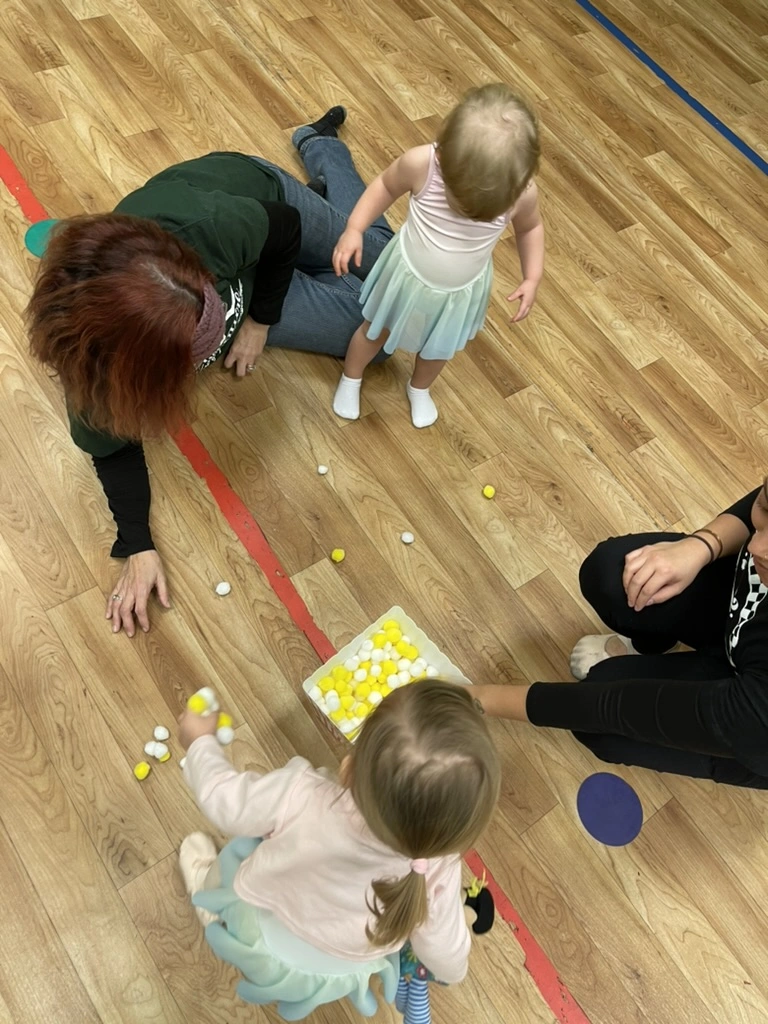 Toddlers and grown-ups playing a pom-pom game together