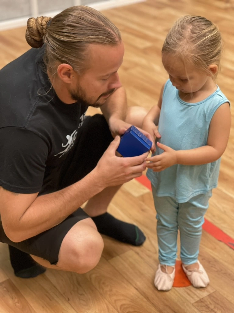 A Bravo Babies teacher showing a toddler a music box in class