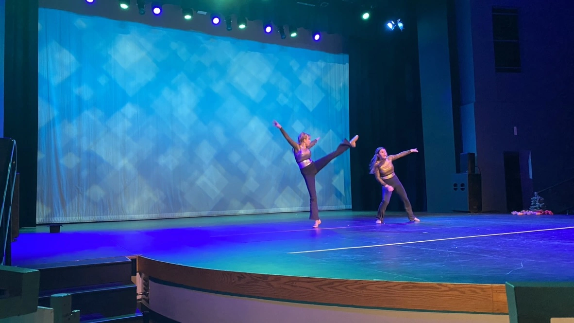 A company duet dancer in a high kick on stage