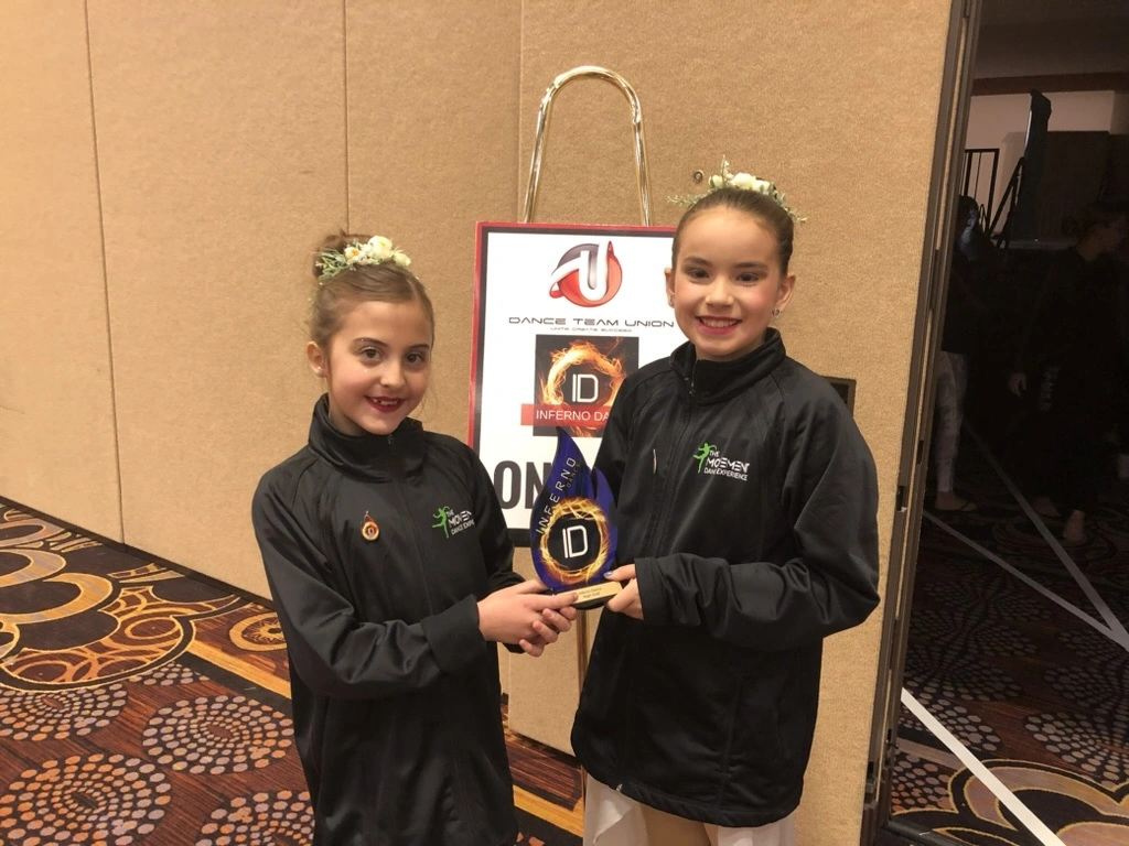 Two company dancers in Movement jackets holding their award