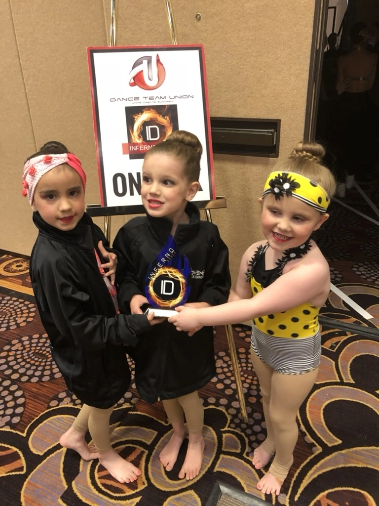 Three mini Movement Dance Company dancers holding their Inferno Dance award