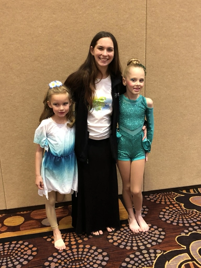 A Movement teacher with two young company dancers at a competition