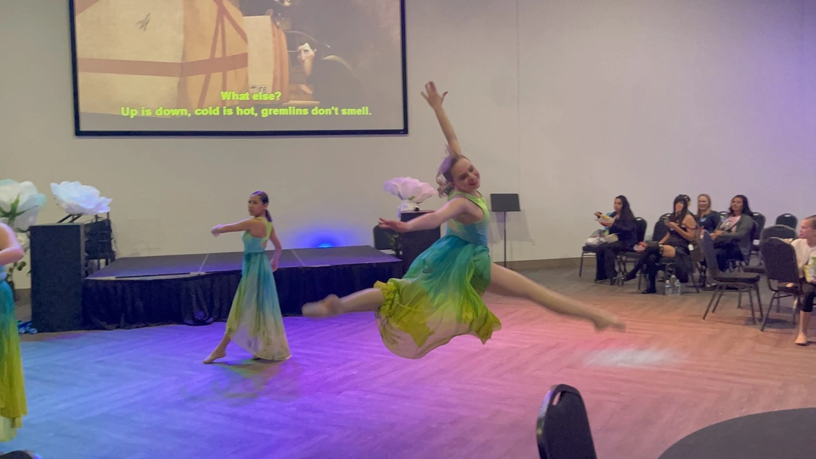 A company dancer leaping in an ombre dress