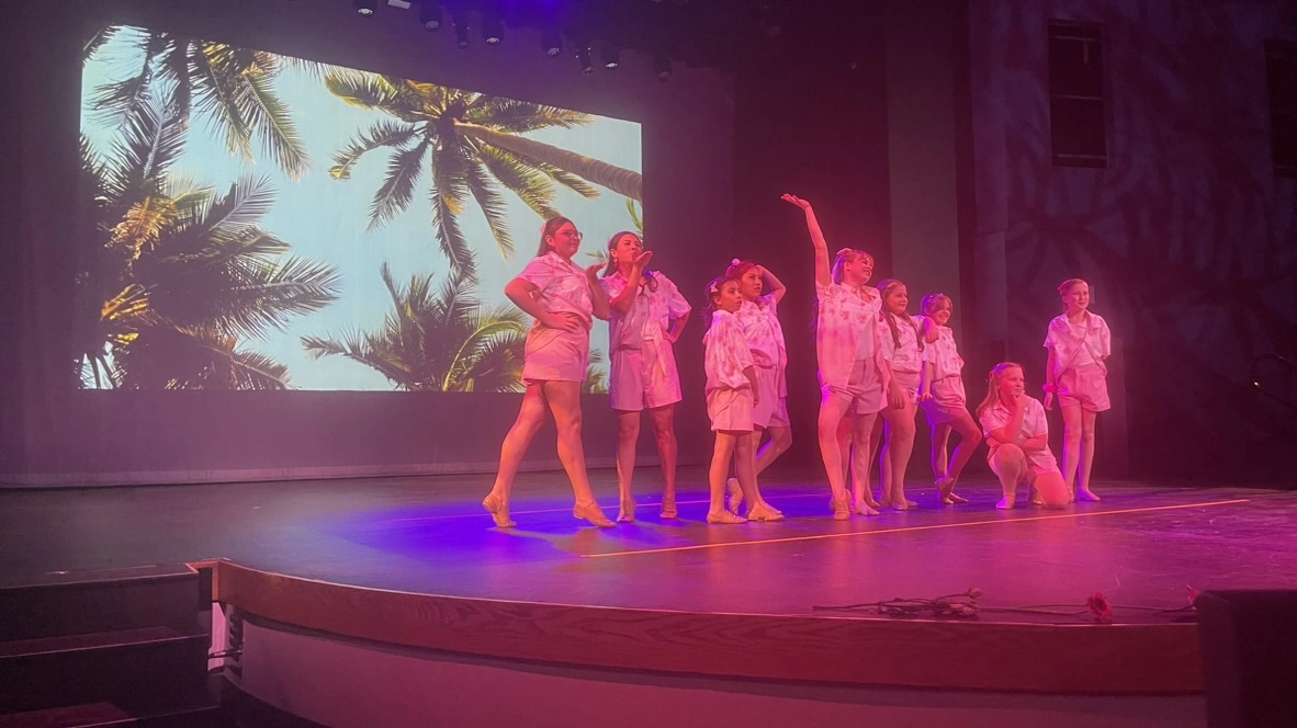 Company dancers striking a pose in front of a tropical backdrop