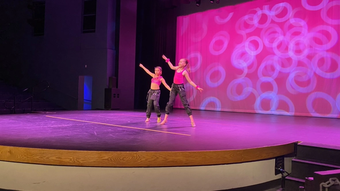 Two young company dancers in pink performing a hip hop duet
