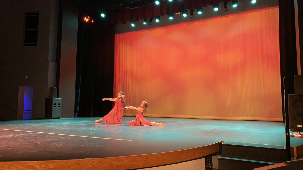 Two company dancers in red dresses performing a lyrical duet
