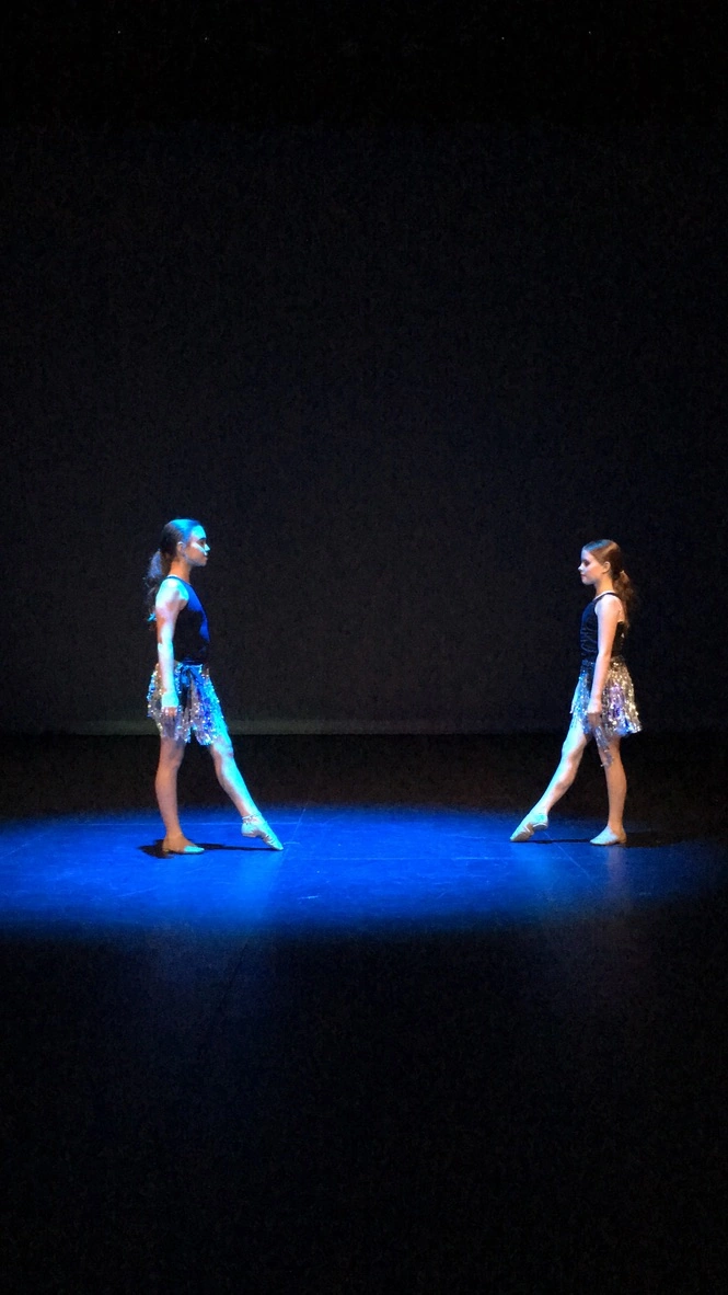 Two company dancers facing each other in a spotlight duet