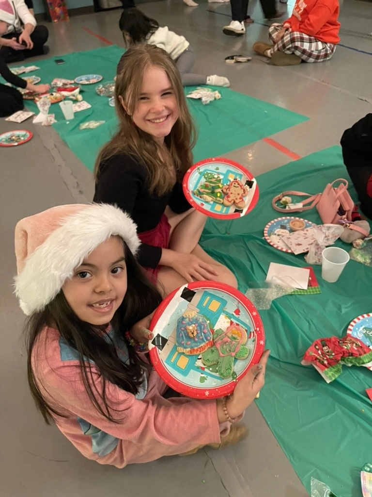 Two girls showing off their decorated holiday cookies at a Movement party