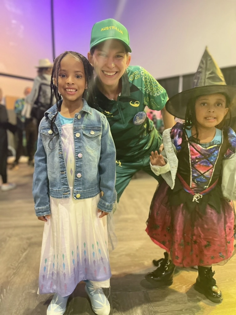 Kids in costumes smiling with a Movement teacher at our Halloween event