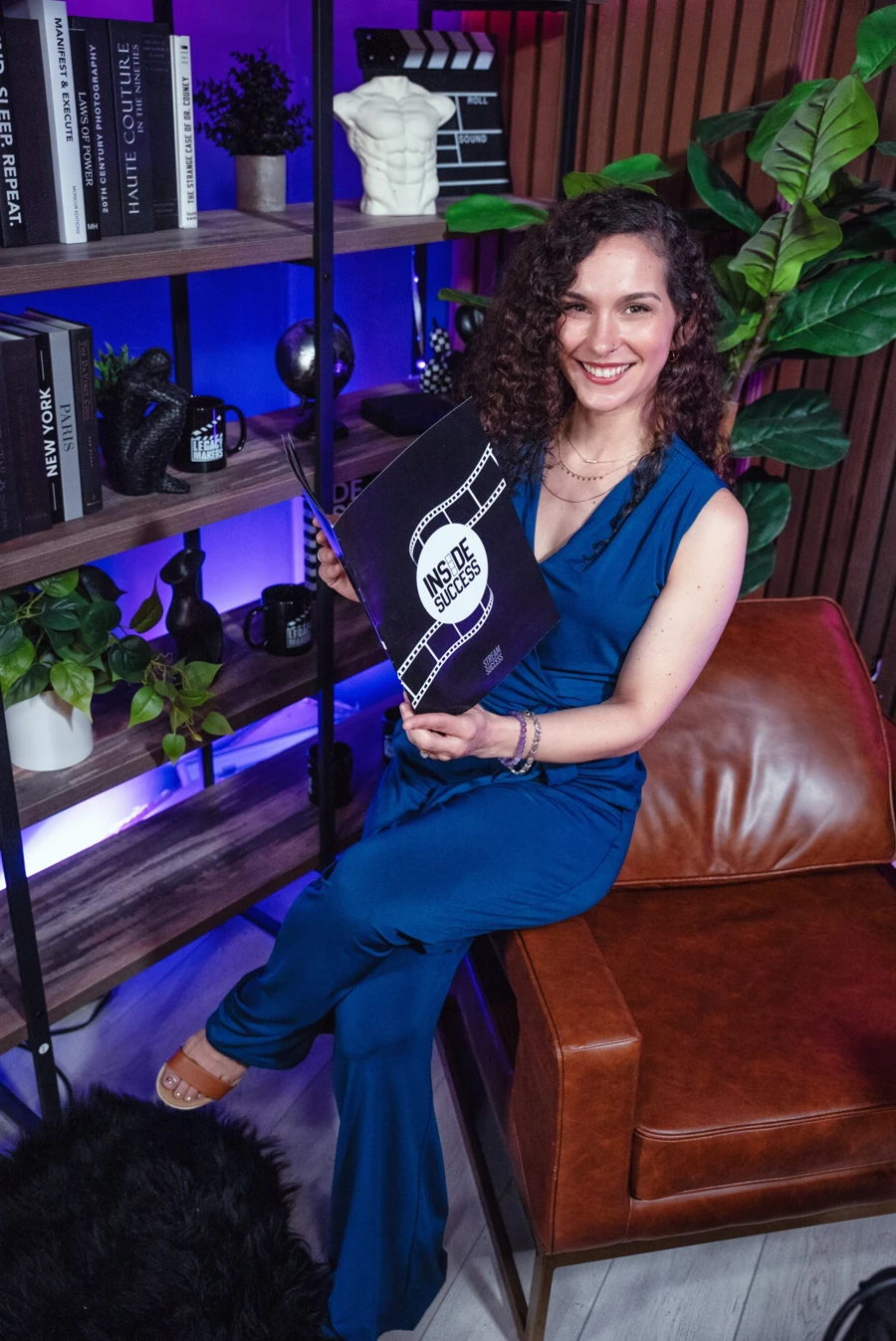 Mandy Saul smiling with an Inside Success magazine on set
