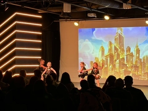 Mini dancers performing in front of a golden city backdrop at Ovation Theatre