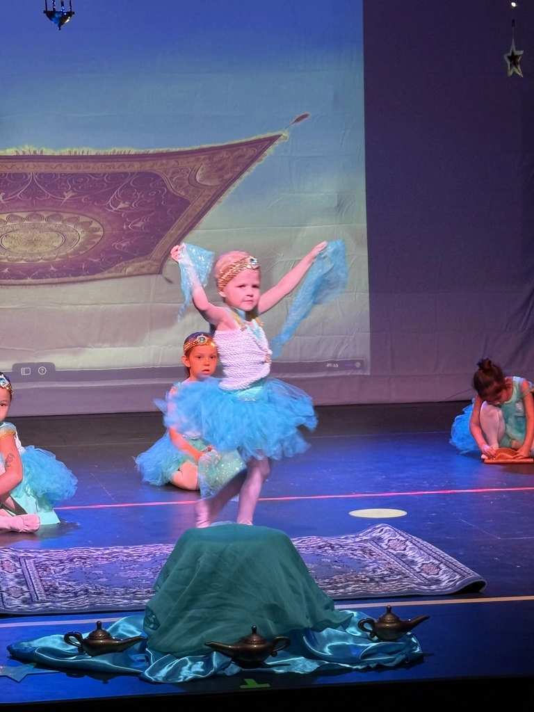 A little ballerina dancing in front of a magic carpet backdrop at a Once Upon A Ballet Aladdin show