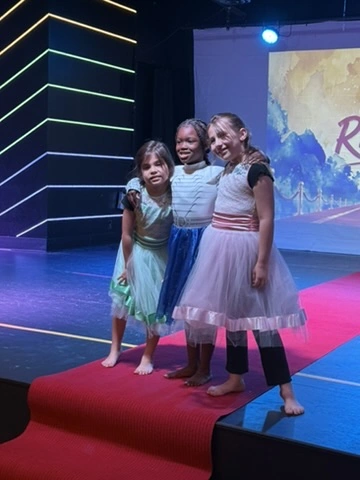 A full cast in sequin skirts posing on the Ovation Theatre stage