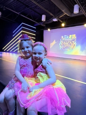Two young performers in sparkly pink costumes