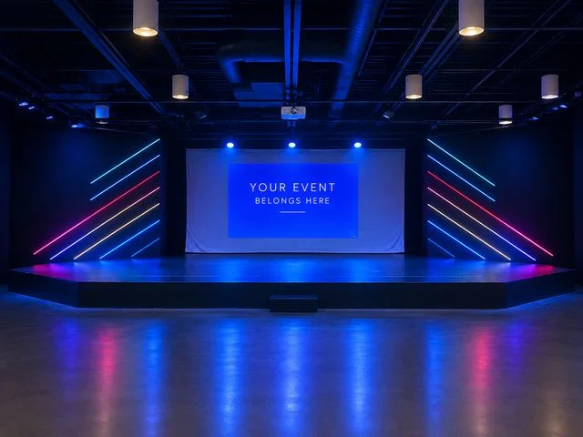 Ovation Theatre stage glowing with colorful lights and a Your Event Belongs Here screen